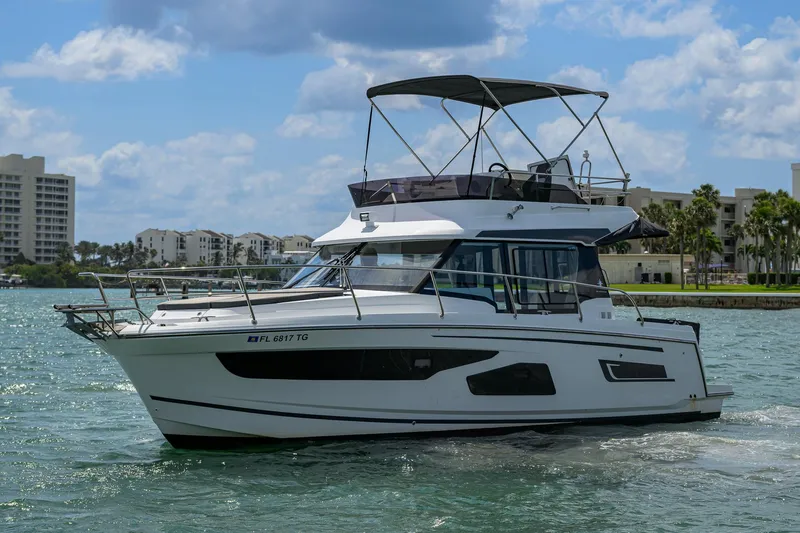 Don't Wake Me Yacht Photos Pics 2022 Jeanneau NC Weekender 1095 Fly boat cruising on a sunny day near waterfront buildings.