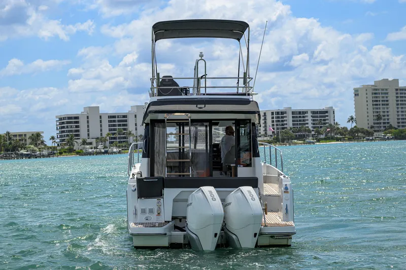 Don't Wake Me Yacht Photos Pics 2022 Jeanneau NC Weekender 1095 Fly cruising on a sunny day near modern buildings.