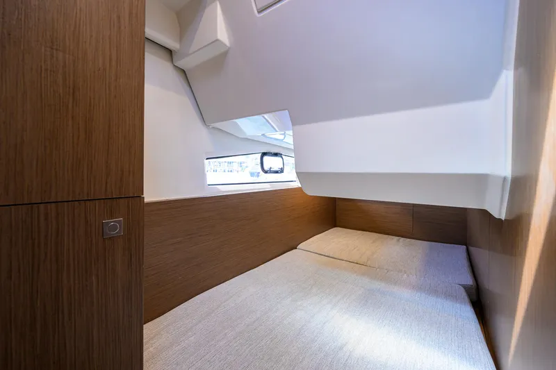 Don't Wake Me Yacht Photos Pics Interior cabin of 2022 Jeanneau NC Weekender 1095 Fly, featuring cozy bedding and wooden accents.