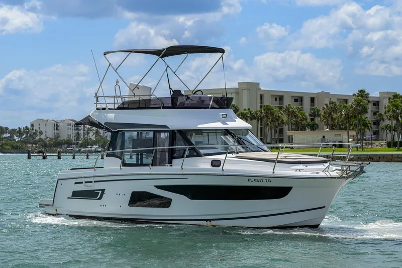 Don't Wake Me Yacht Photos Pics 2022 Jeanneau NC Weekender 1095 Fly cruising on a sunny day near waterfront buildings.