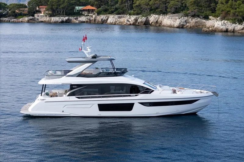  Yacht Photos Pics 2024 Azimut Fly 68 yacht cruising on serene waters near rocky coastline.