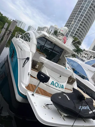  Yacht Photos Pics 2010 Beneteau Monte Carlo 47 yacht docked with jet ski, city skyline in background.