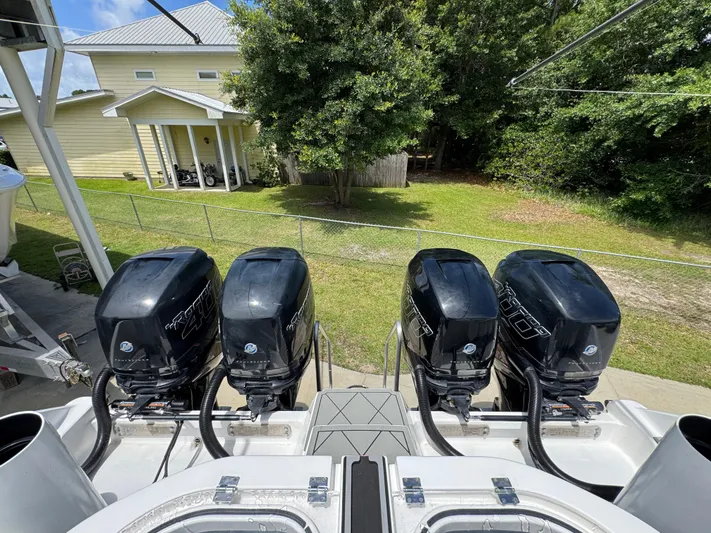  Yacht Photos Pics Four powerful outboard motors on a 2020 Invincible 40 Catamaran, parked near a house.