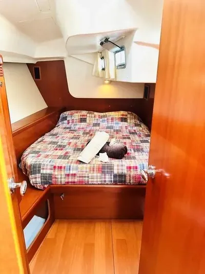 Karuna Ss Yacht Photos Pics Cozy cabin interior of 2007 Beneteau 49' Cruiser with plaid bedding and wooden finishes.