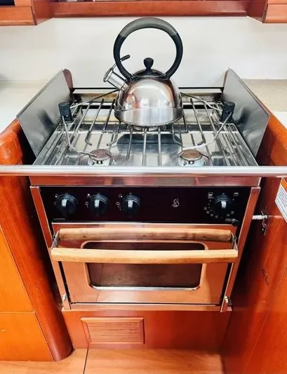Karuna Ss Yacht Photos Pics 2007 Beneteau 49' Cruiser kitchen with stove and kettle, featuring wooden cabinetry.