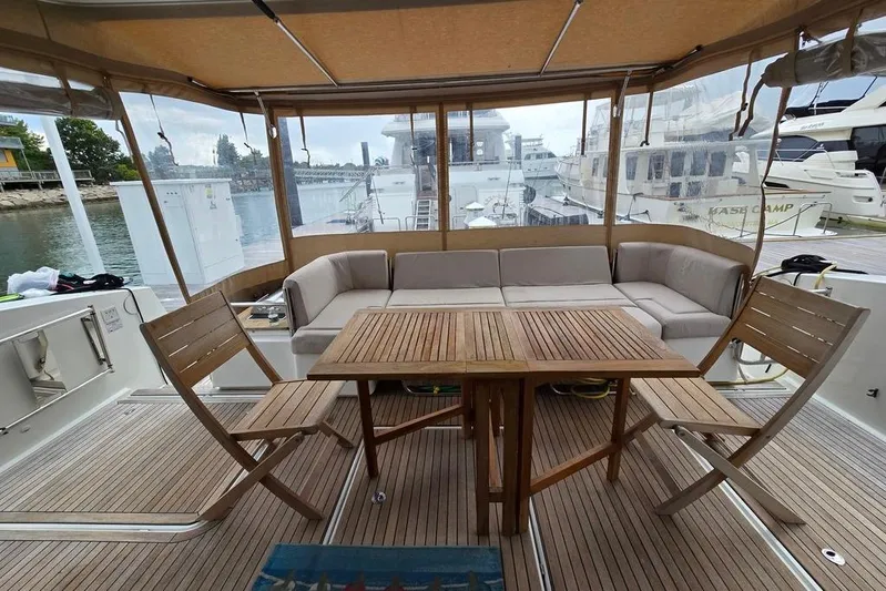 Vie Pure Yacht Photos Pics Outdoor seating area on 2021 Fountaine Pajot MY4.S yacht with wooden furniture and marina view.