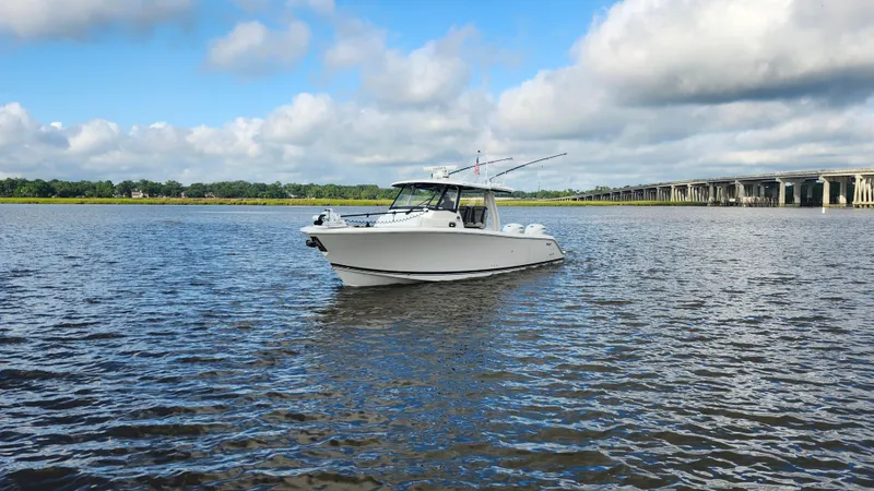 Blown Dough Yacht Photos Pics 2023 Pursuit S 358 Sport boat on calm water under a cloudy sky.