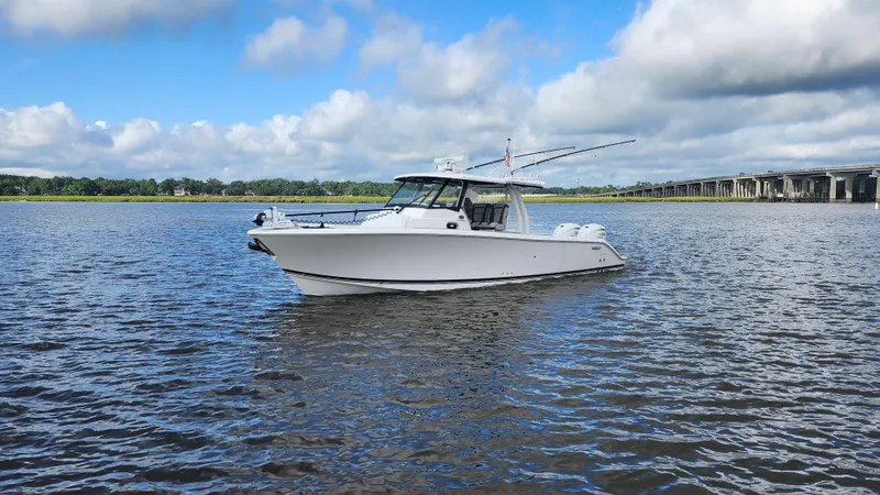 Blown Dough Yacht Photos Pics 2023 Pursuit S 358 Sport boat on calm water under a partly cloudy sky.