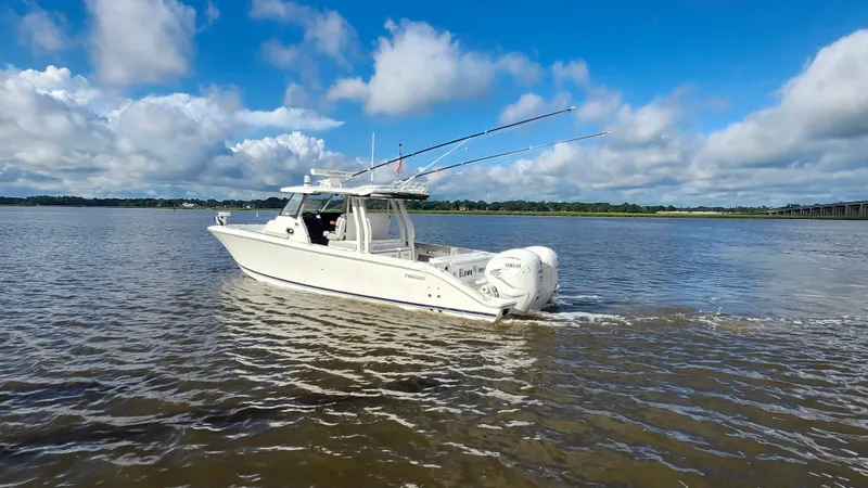 Blown Dough Yacht Photos Pics 2023 Pursuit S 358 Sport boat cruising on a calm river under a blue sky.