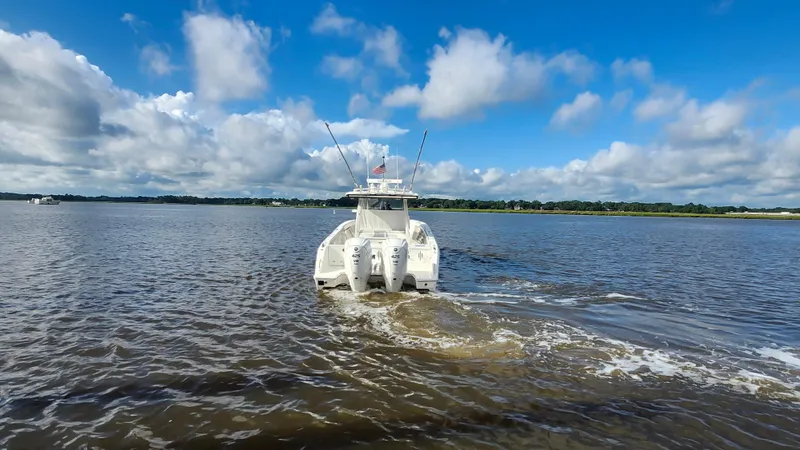 Blown Dough Yacht Photos Pics 2023 Pursuit S 358 Sport boat cruising on a calm lake under a blue sky.