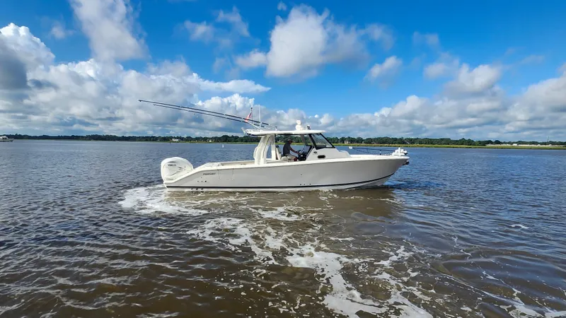 Blown Dough Yacht Photos Pics 2023 Pursuit S 358 Sport boat cruising on a calm lake under a blue sky.