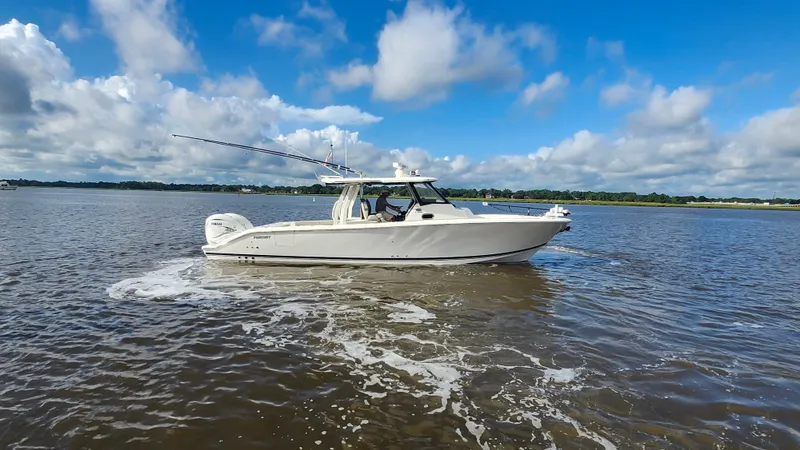 Blown Dough Yacht Photos Pics 2023 Pursuit S 358 Sport boat cruising on a calm lake under a blue sky.