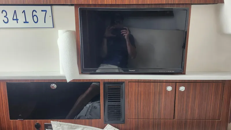 Blown Dough Yacht Photos Pics 2023 Pursuit S 358 Sport interior with TV, wood paneling, and storage cabinets.