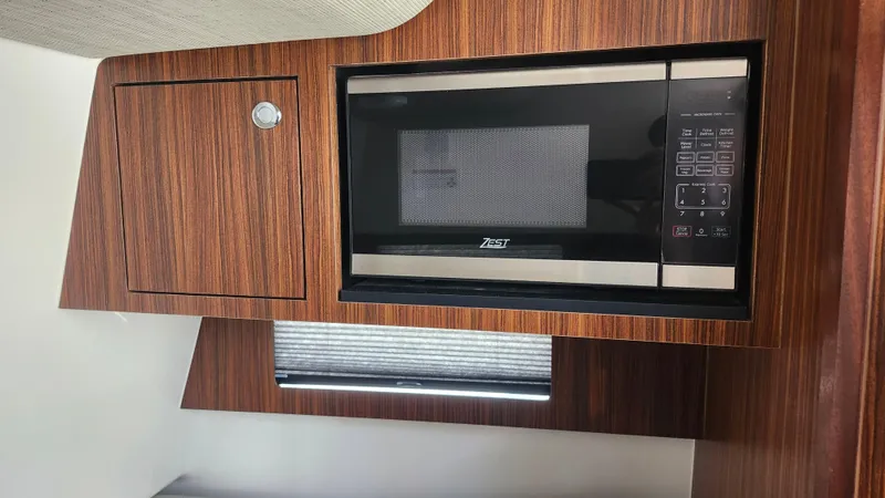 Blown Dough Yacht Photos Pics 2023 Pursuit S 358 Sport interior with wood paneling and built-in microwave.