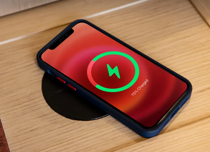 Aquila 70 Yacht Photos Pics Smartphone wirelessly charging on wooden surface, displaying 76% charged.