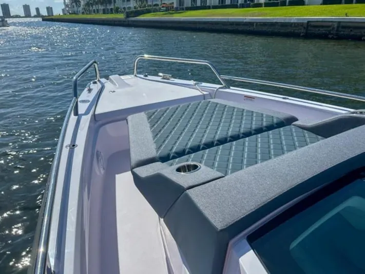  Yacht Photos Pics 2024 Axopar 37XC CROSS CABIN boat with cushioned deck, cruising on a sunny waterway.