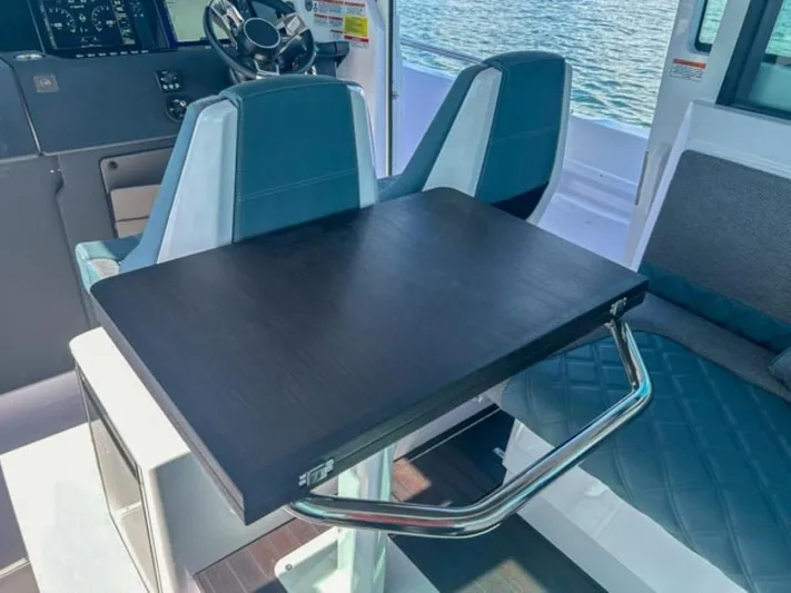  Yacht Photos Pics 2024 Axopar 37XC CROSS CABIN interior with seating and table, overlooking water.