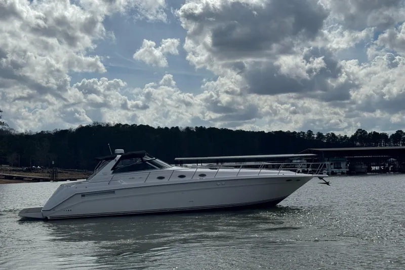  Yacht Photos Pics 1996 Sea Ray 500 Sedan Bridge yacht on a calm lake under cloudy skies.
