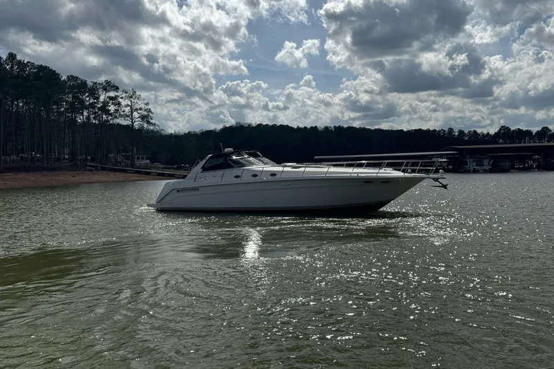  Yacht Photos Pics 1996 Sea Ray 500 Sedan Bridge yacht on a serene lake under cloudy skies.
