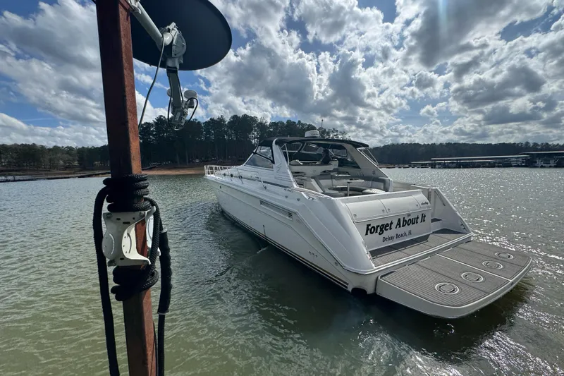  Yacht Photos Pics 1996 Sea Ray 500 Sedan Bridge yacht on a serene lake under a cloudy sky.