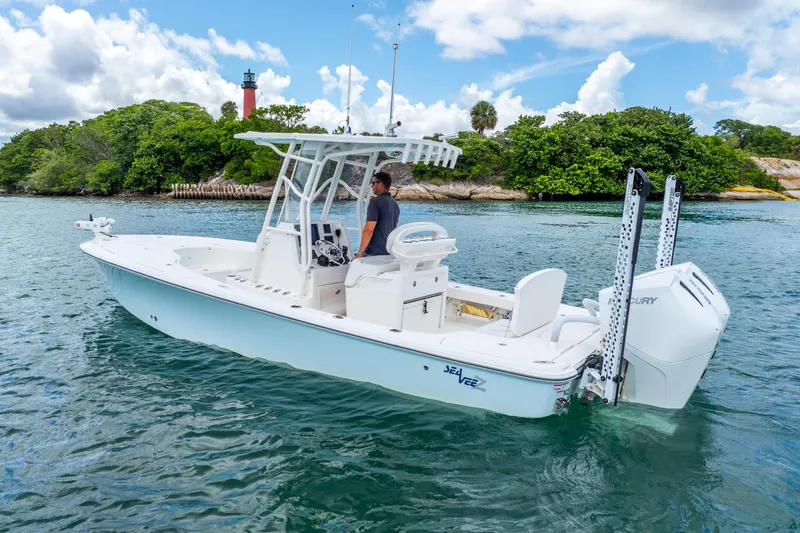  Yacht Photos Pics 2022 SeaVee 270Z boat on water, lush greenery, and lighthouse in background.