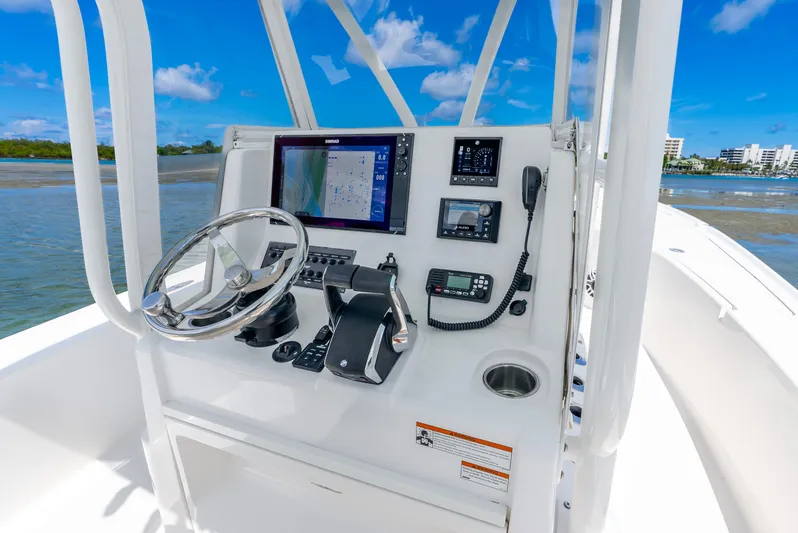  Yacht Photos Pics 2022 SeaVee 270Z boat console with navigation equipment and steering wheel, on calm waters.