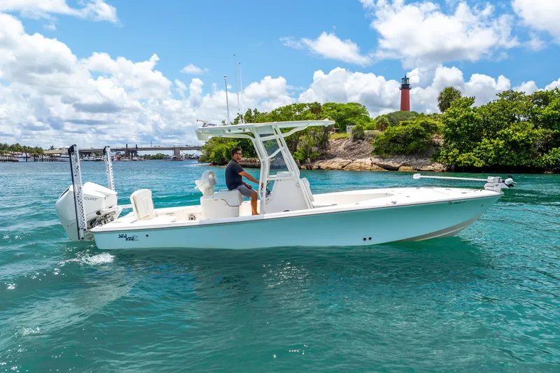  Yacht Photos Pics 2022 SeaVee 270Z boat cruising on clear blue water near a lighthouse.