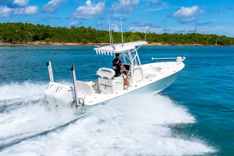  Yacht Photos Pics 2022 SeaVee 270Z boat cruising on blue water near lush green shoreline.