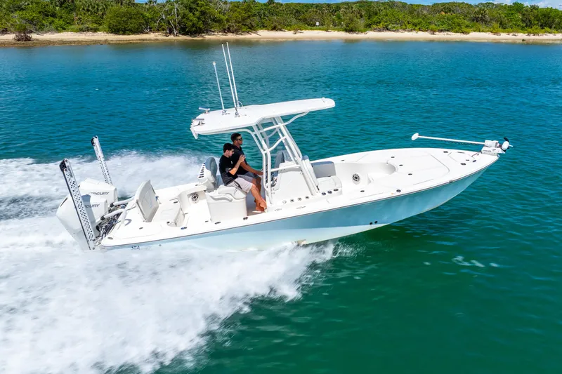  Yacht Photos Pics 2022 SeaVee 270Z boat cruising on clear blue water near a sandy shoreline.
