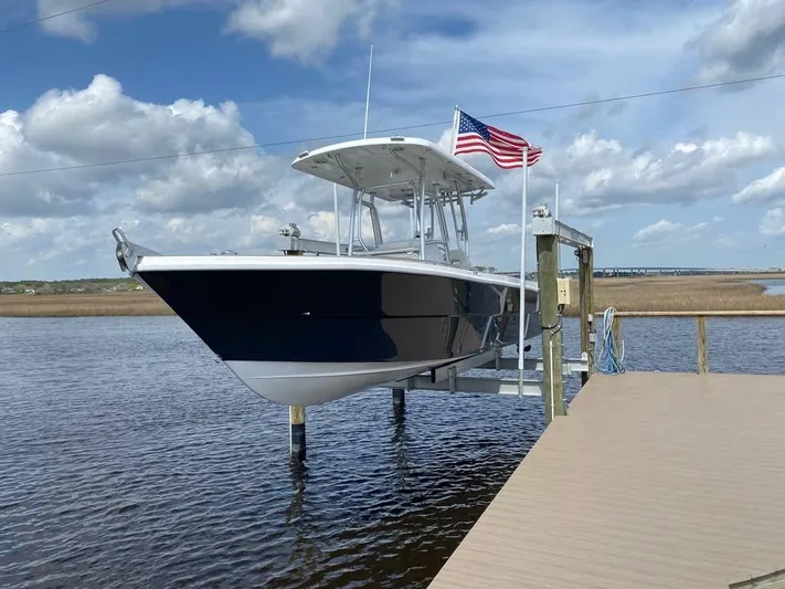  Yacht Photos Pics A 2025 Custom Shark Fin R321 boat docked, with an American flag, under a partly cloudy sky.