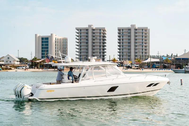  Yacht Photos Pics 2020 Intrepid 407 Cuddy boat cruising near modern beachfront buildings.