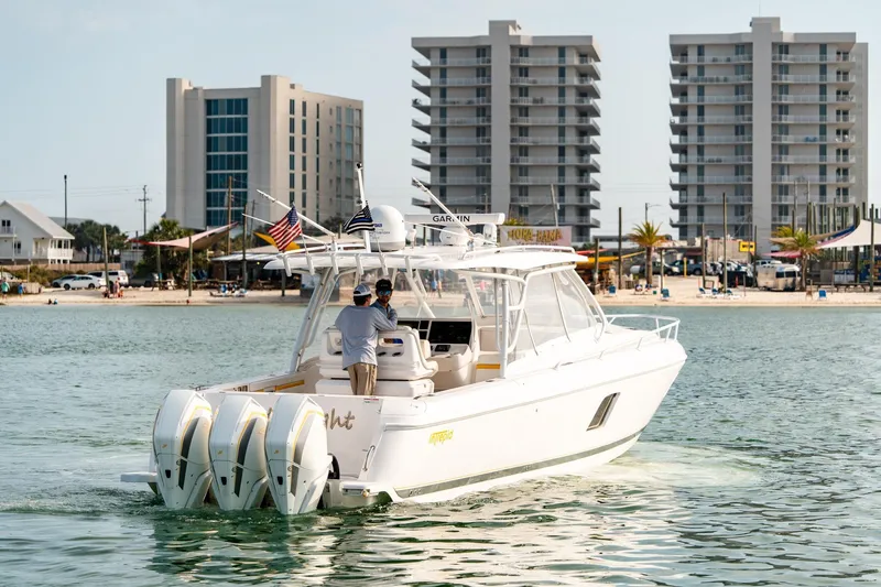 Yacht Photos Pics 2020 Intrepid 407 Cuddy boat cruising near beachfront buildings and palm trees.