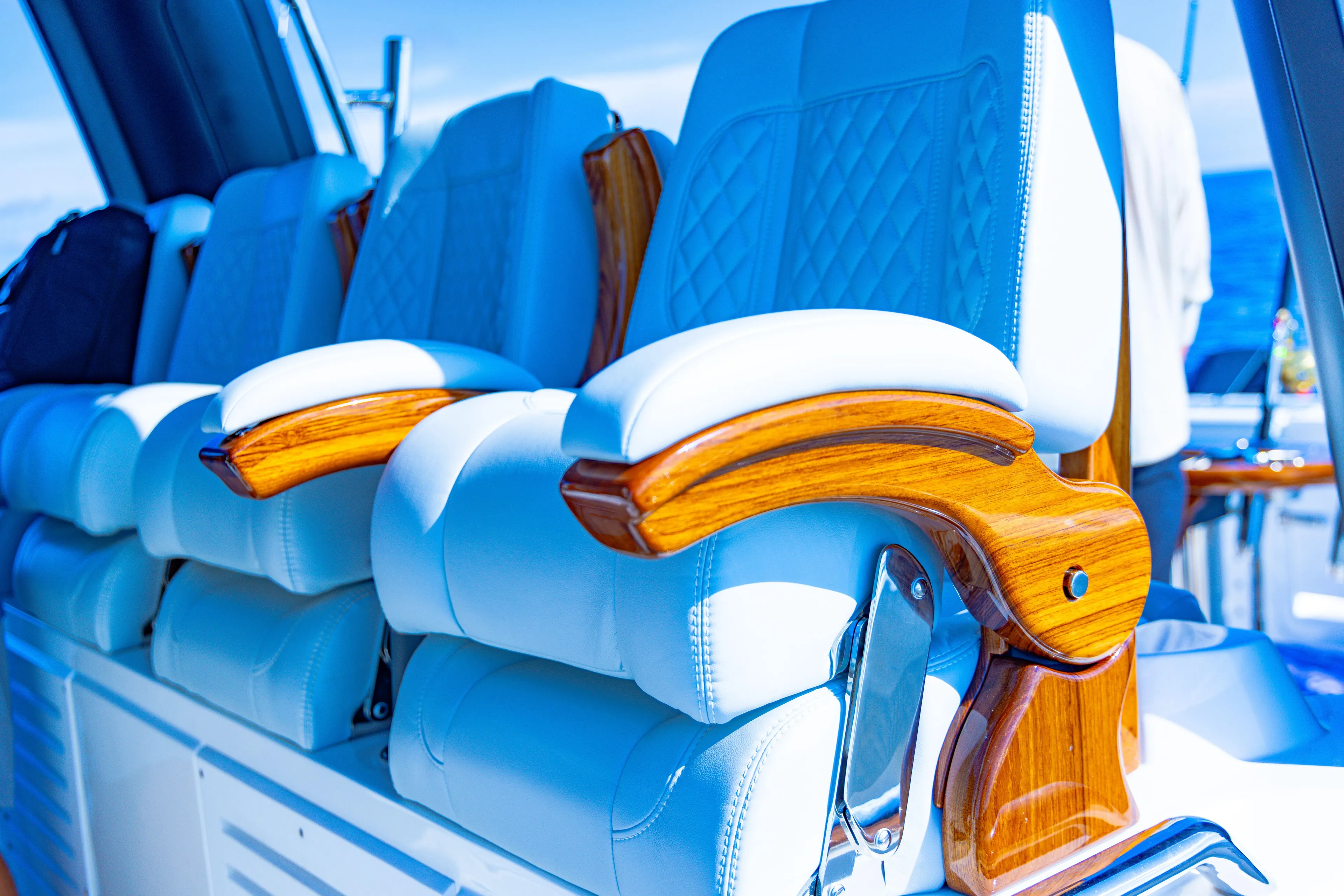  Yacht Photos Pics Luxurious seating on 2024 Aquila 47 Molokai yacht with wooden armrests and white upholstery.