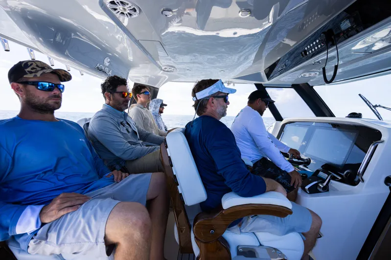  Yacht Photos Pics Group of people navigating a 2024 Aquila 47 Molokai boat, focused on the controls.