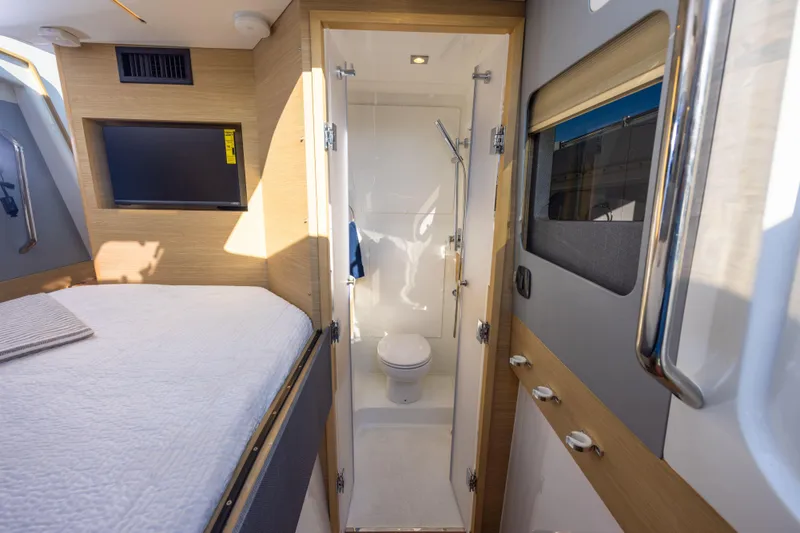  Yacht Photos Pics 2024 Aquila 47 Molokai yacht interior with bed, TV, and compact bathroom.