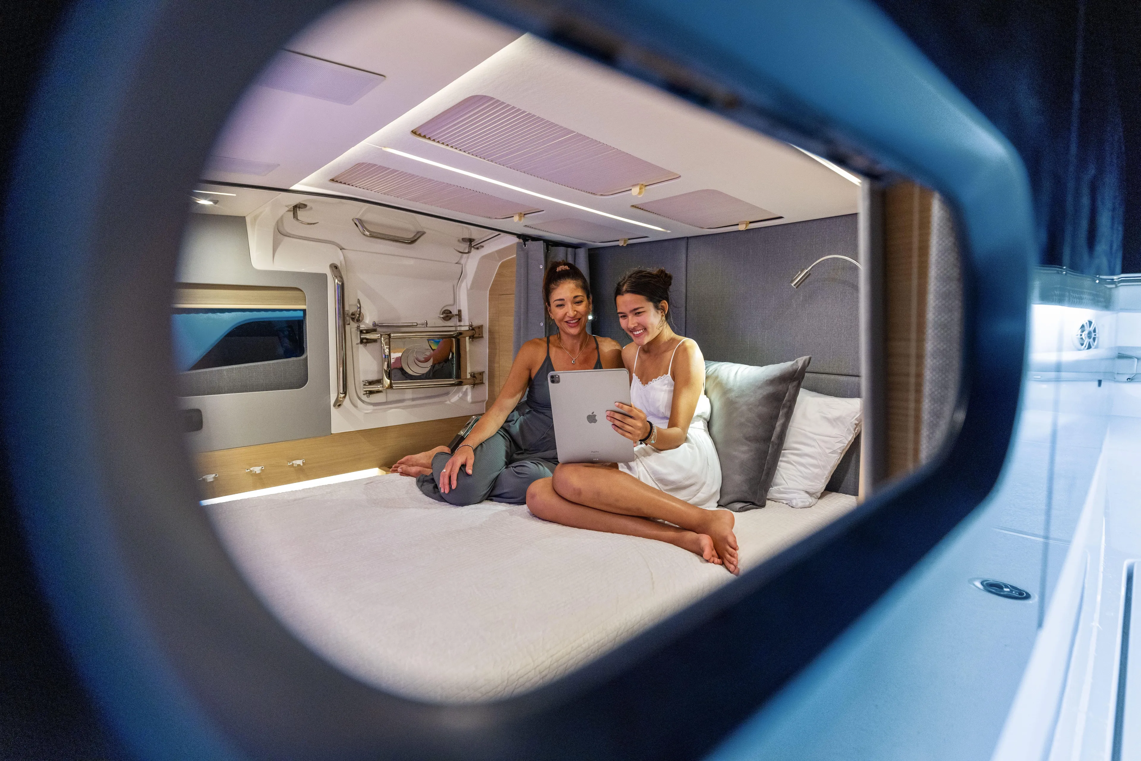  Yacht Photos Pics Two people relaxing with a tablet in a 2024 Aquila 47 Molokai cabin.