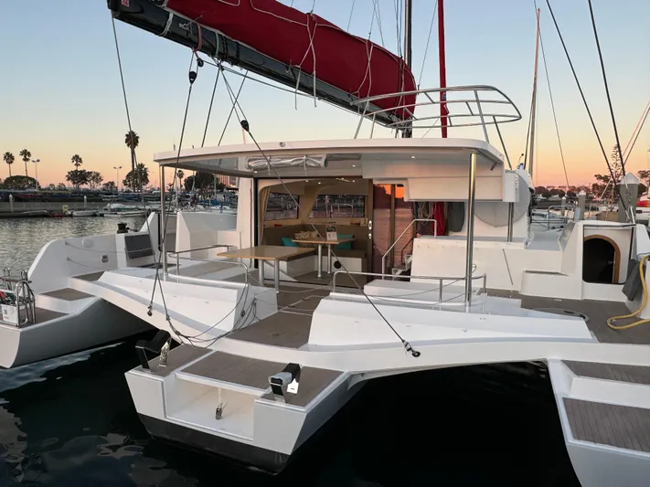 Stock Neel 47 Yacht Photos Pics 2023 NEEL 47 trimaran docked at sunset, featuring spacious deck and modern design.