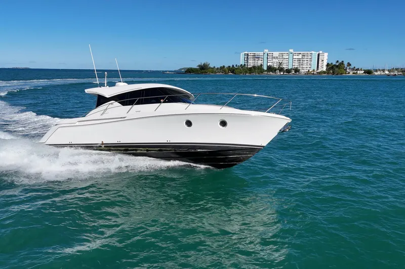 Pal Agua Yacht Photos Pics 2023 Tiara Yachts C39 Coupe cruising on blue ocean near coastal buildings.