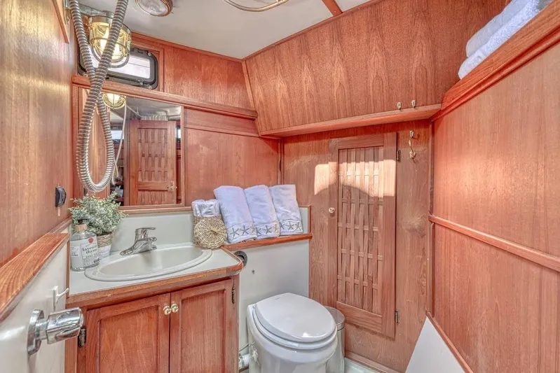  Yacht Photos Pics Wood-paneled boat bathroom with sink, toilet, and towels; Nielsen 46, 1981 model.