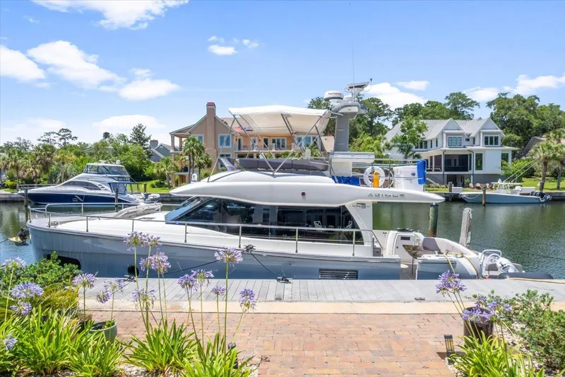 Tangerine Moon Yacht Photos Pics Azimut Magellano 43 yacht docked in a scenic marina, surrounded by lush greenery and waterfront homes.