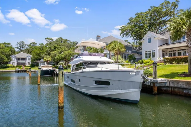 Tangerine Moon Yacht Photos Pics 2014 Azimut Magellano 43 yacht docked by waterfront homes, surrounded by lush greenery.
