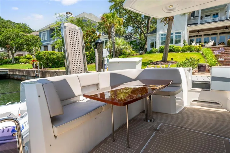 Tangerine Moon Yacht Photos Pics Luxurious Azimut Magellano 43 yacht deck with elegant seating and table, docked near waterfront homes.