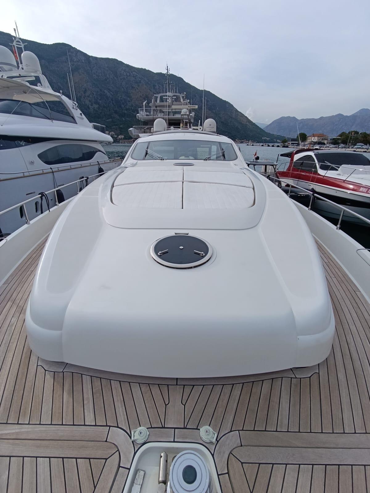 2005 Pershing 76 yacht with sleek design, docked in a marina, surrounded by mountains.