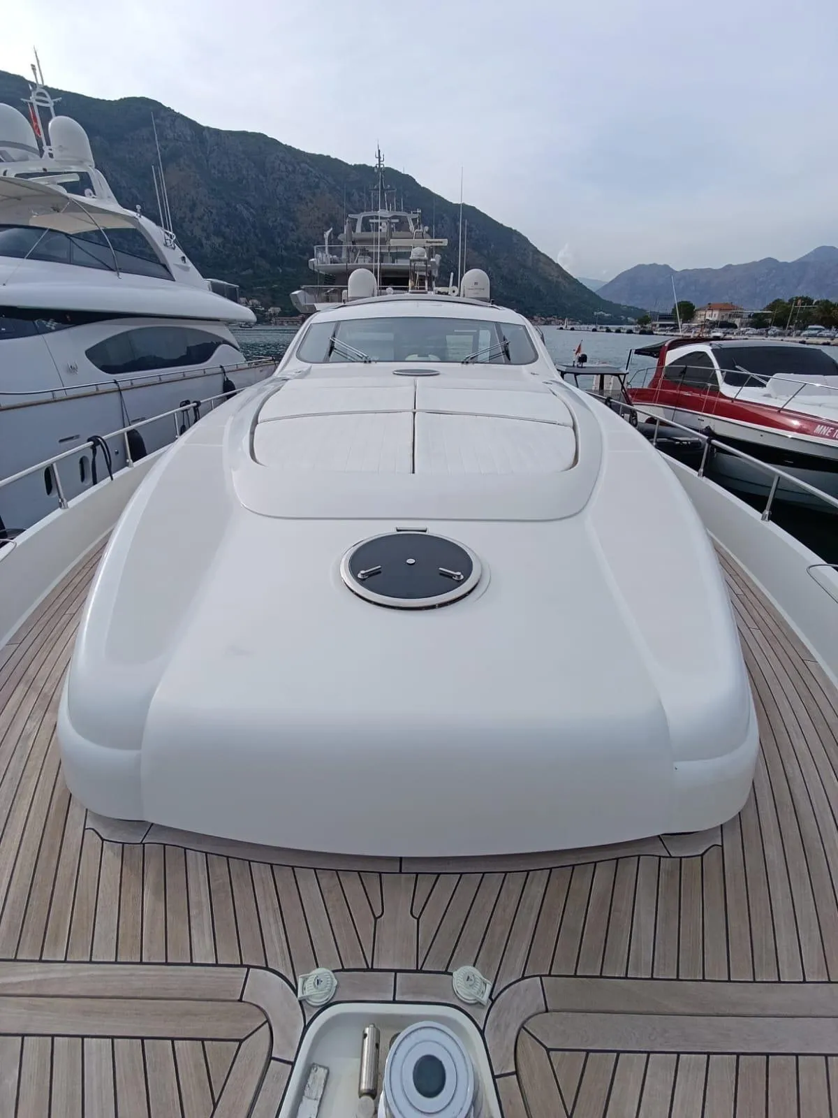 2005 Pershing 76 yacht with sleek design, docked in a marina, surrounded by mountains.