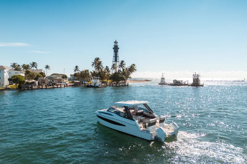Era Ora Yacht Photos Pics Aquila 32 Sport 2022 boat cruising near a lighthouse on a sunny day.