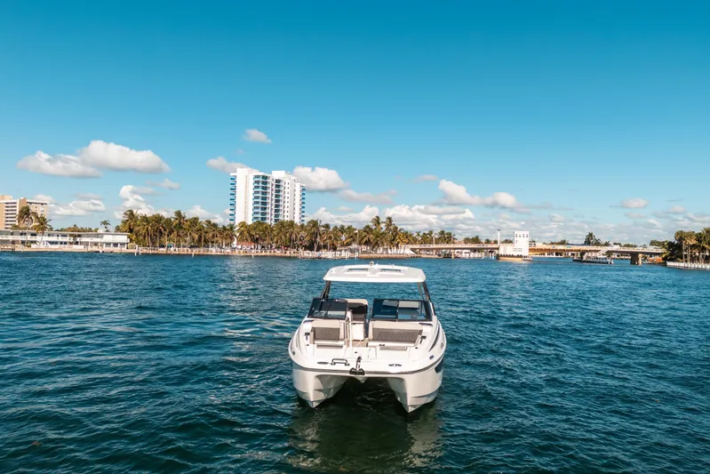 Era Ora Yacht Photos Pics Aquila 32 Sport 2022 boat on water with cityscape and palm trees in background.