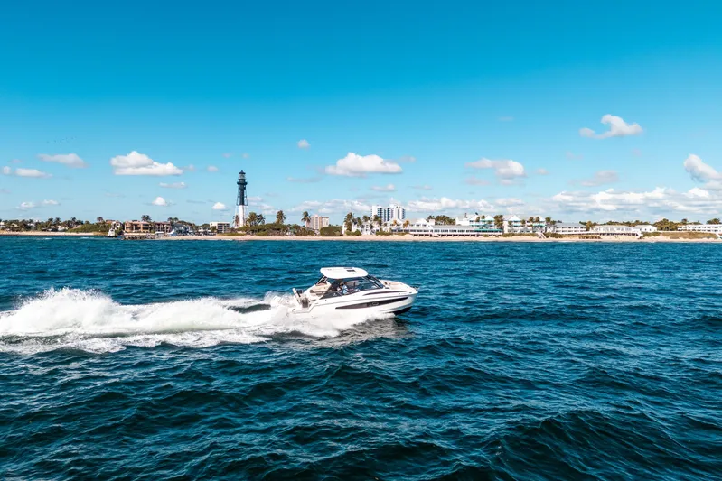 Era Ora Yacht Photos Pics Aquila 32 Sport 2022 cruising on blue ocean near coastal cityscape.