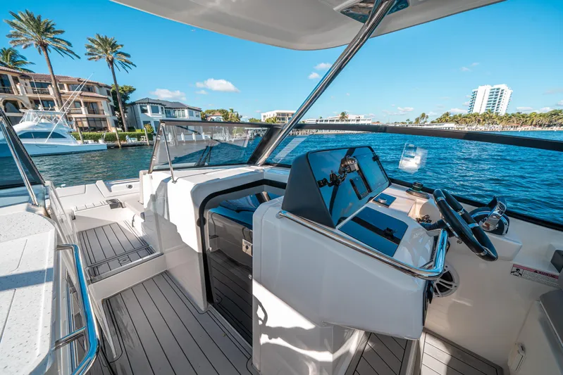 Era Ora Yacht Photos Pics 2022 Aquila 32 Sport boat interior with modern helm, docked near waterfront homes.