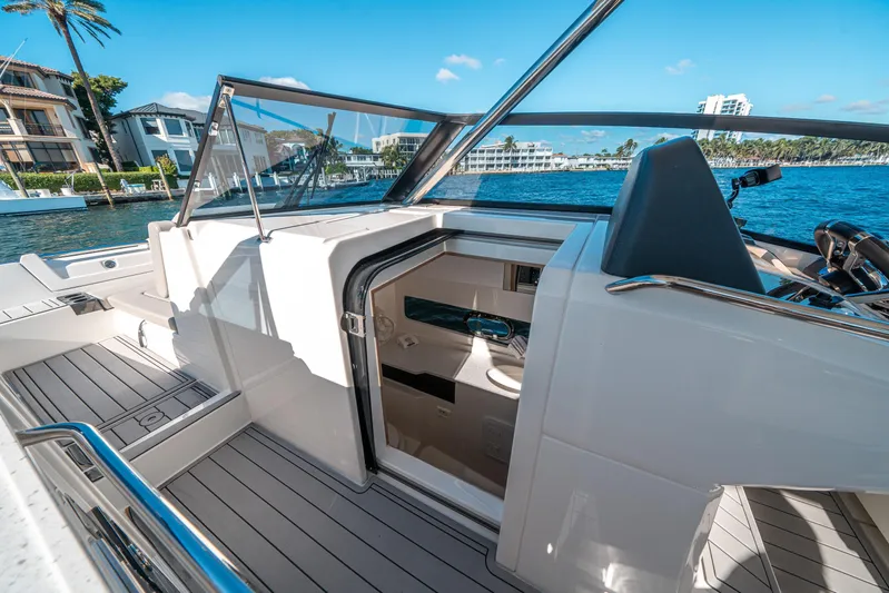 Era Ora Yacht Photos Pics 2022 Aquila 32 Sport yacht interior with open cabin door, docked by waterfront homes.