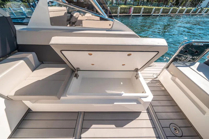 Era Ora Yacht Photos Pics Open storage compartment on 2022 Aquila 32 Sport boat, docked by the water.
